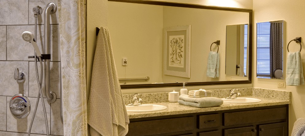 A bathroom with a large mirror, beige walls, and neatly arranged towels on the countertop.