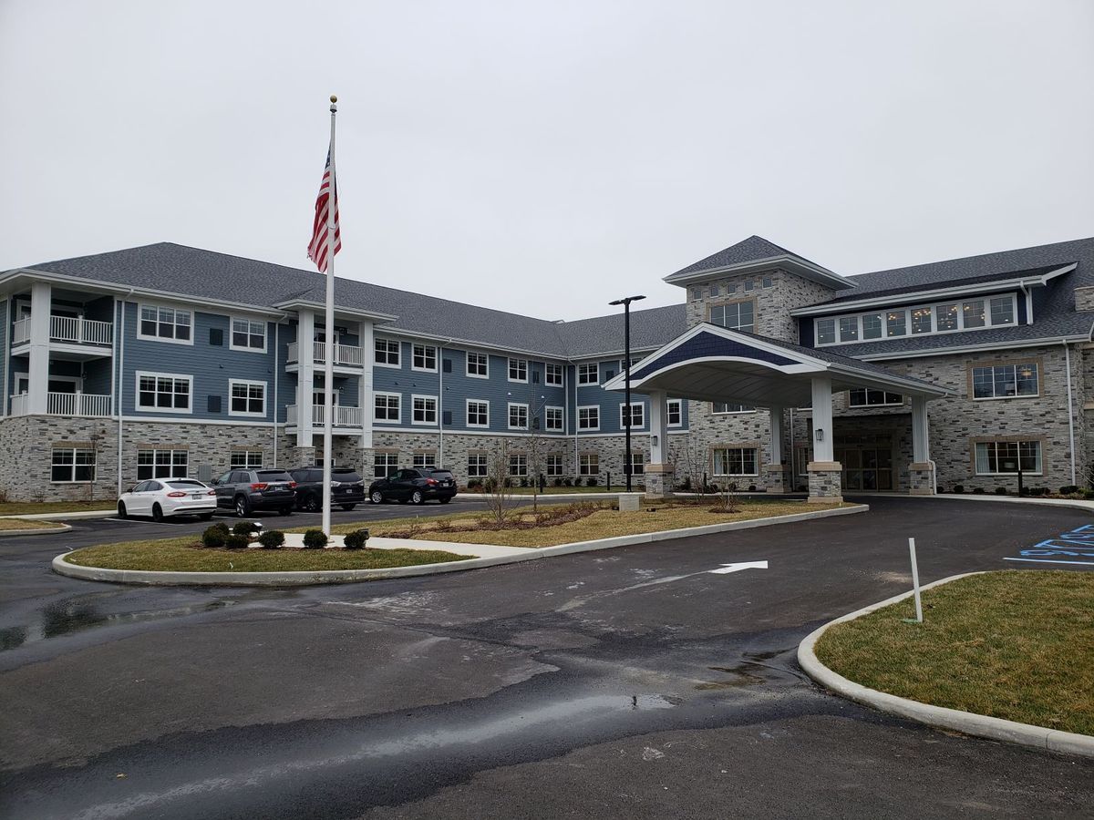 A large building with a prominent entrance and an American flagpole in the foreground.
