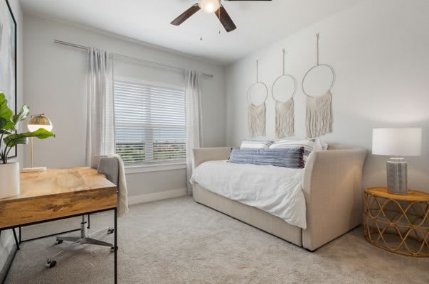 A cozy bedroom featuring a daybed with modern decor and dreamcatchers on the wall.