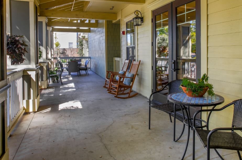 A cozy porch with rocking chairs and a table, bathed in sunlight.