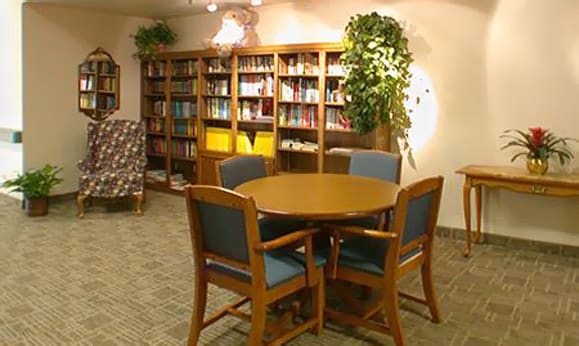 A cozy library reading area with a round table and bookshelves.