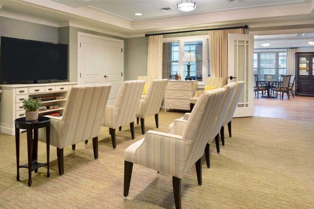 A well-arranged conference room with beige chairs and carpet flooring.