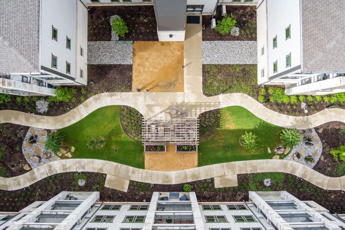 Aerial view of a modern courtyard with landscaped pathways and green spaces between buildings.