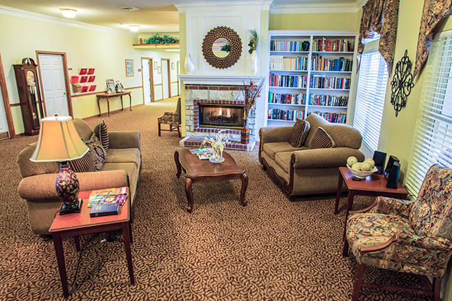 A cozy living room with comfortable seating, a fireplace, and a bookshelf.
