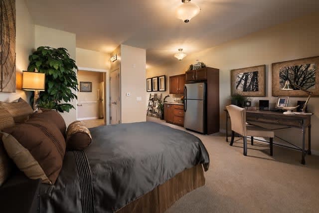 A cozy apartment interior featuring a bedroom with a kitchenette and workspace.