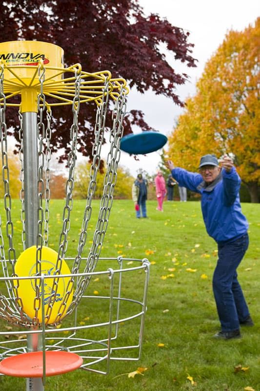 A person enjoying a game of disc golf in an autumn setting.