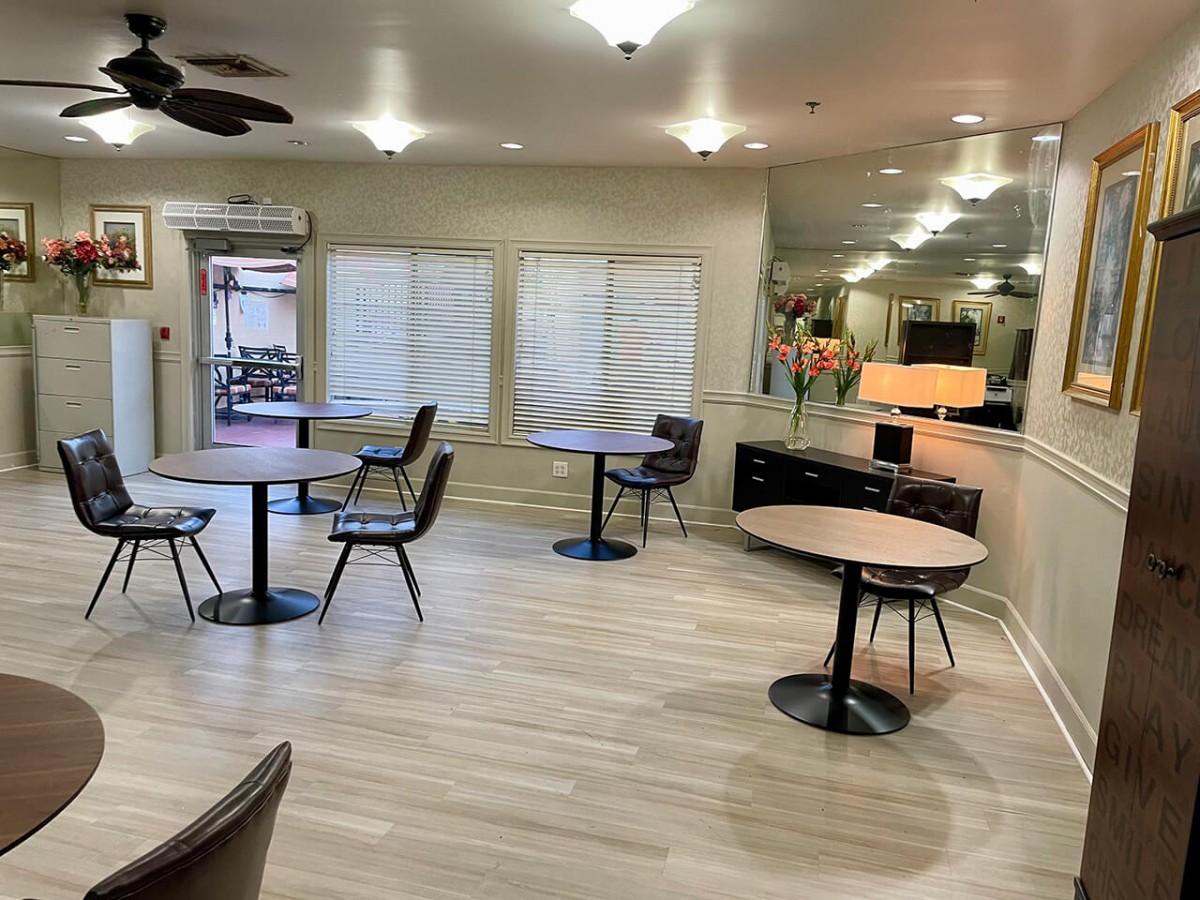 A modern dining area with tables and chairs arranged on wooden flooring and bright lighting.