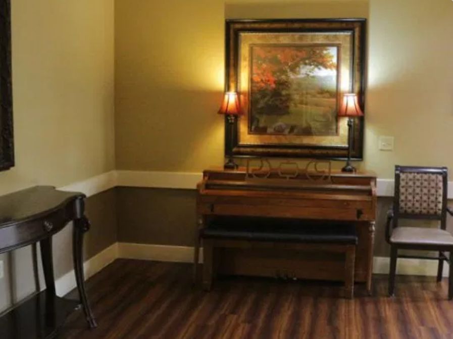 A cozy interior featuring a piano, wall art, and soft lighting from lamps.