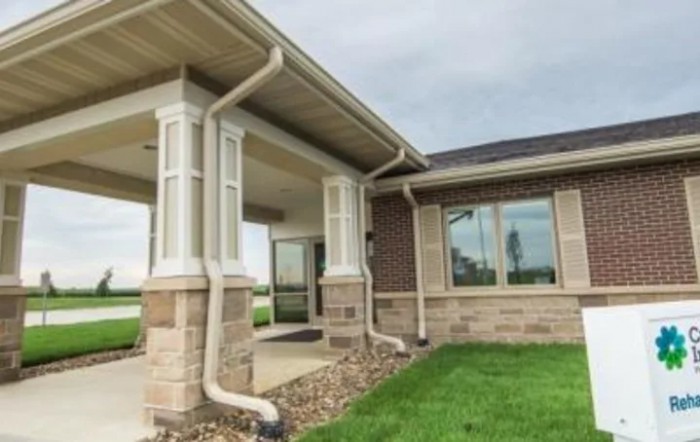 A view of a house exterior with a front porch and well-maintained lawn.