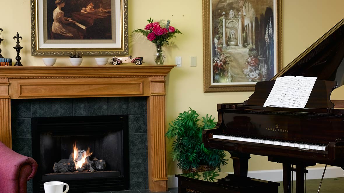 A cozy living room with a fireplace, grand piano, and vibrant artwork.