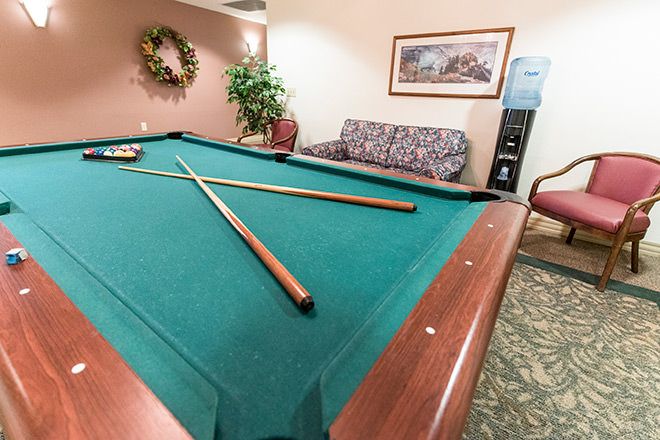 A cozy recreation room featuring a pool table with cue sticks, surrounded by comfortable seating and decor.