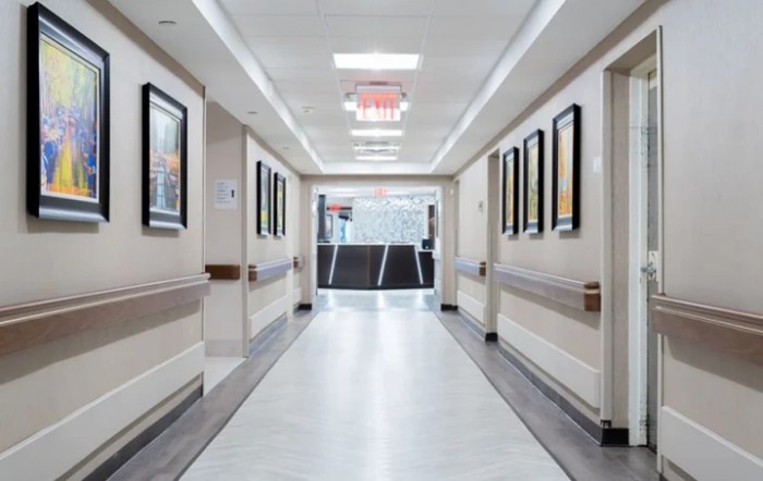 A clean and well-lit hospital corridor with framed artwork on the walls.