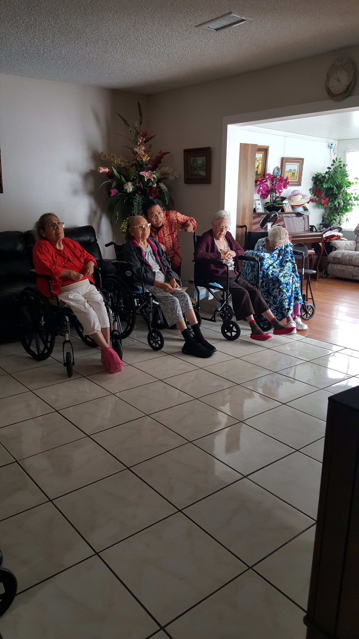 A group of seniors sitting in wheelchairs in a living room setting.