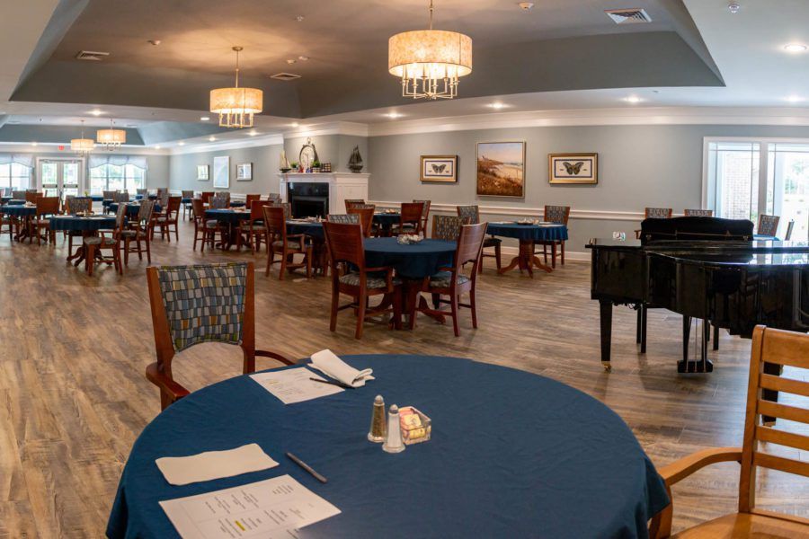 An elegant dining room with neatly arranged tables and chairs, adorned with chandeliers.