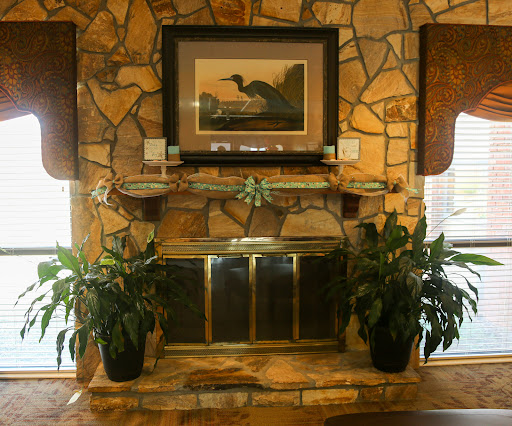 A cozy living room featuring a stone fireplace adorned with plants and an artwork above.