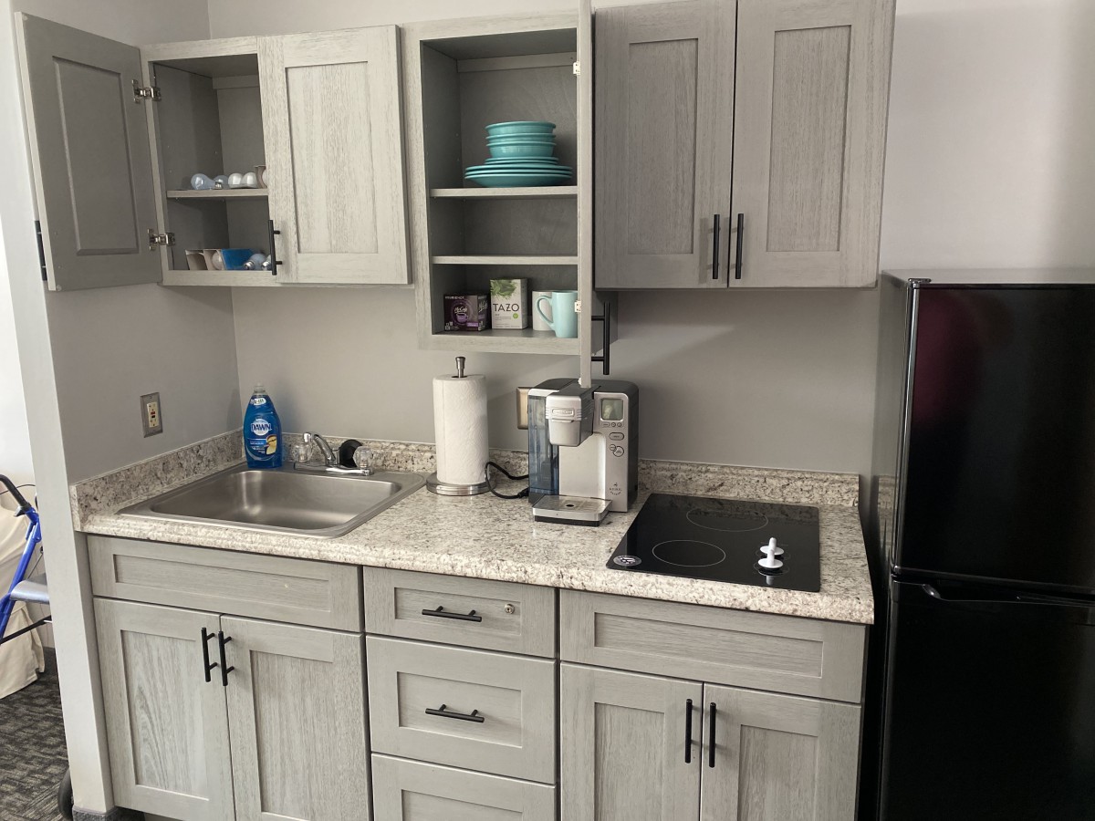 A modern kitchen setup with grey cabinets, a sink, and various appliances on the countertop.