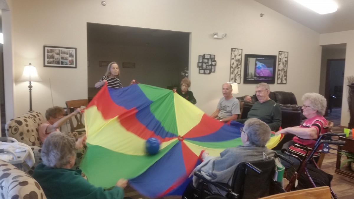 A group of elderly individuals engaging in a parachute game at a nursing home.