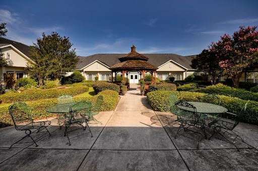 A scenic outdoor view of a building surrounded by well-maintained gardens and seating areas.