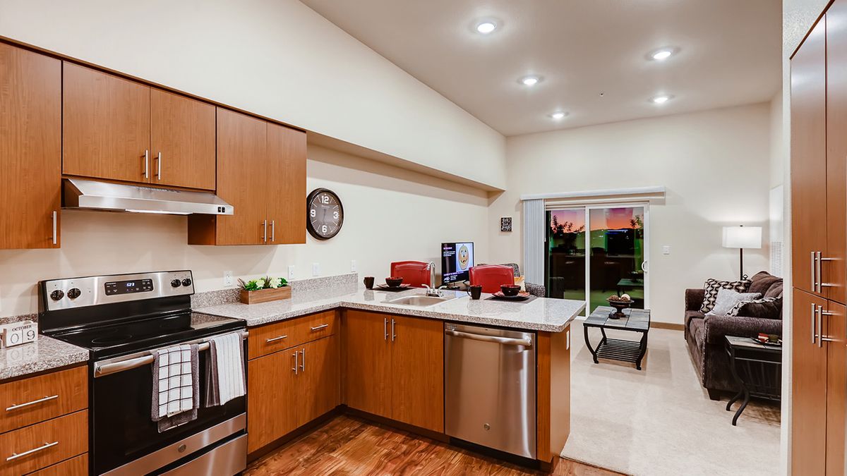 A modern kitchen with wood cabinets, stainless steel appliances, and a connected dining area.