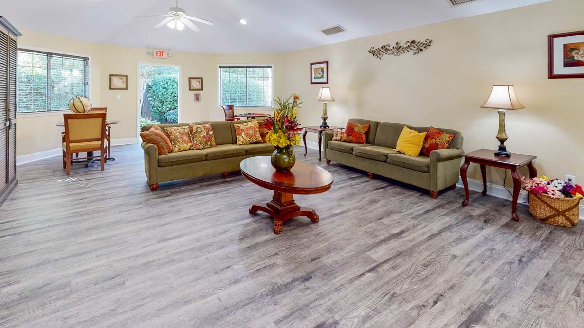 A cozy living room with two sofas, a central coffee table, and large windows providing natural light.