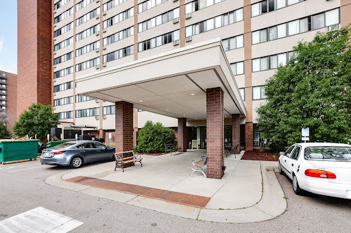 Entrance of a multi-story apartment building with a covered area for parking.