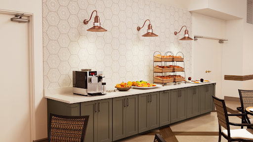 A modern kitchen area featuring a coffee machine, decorative lighting, and a variety of breakfast items displayed.