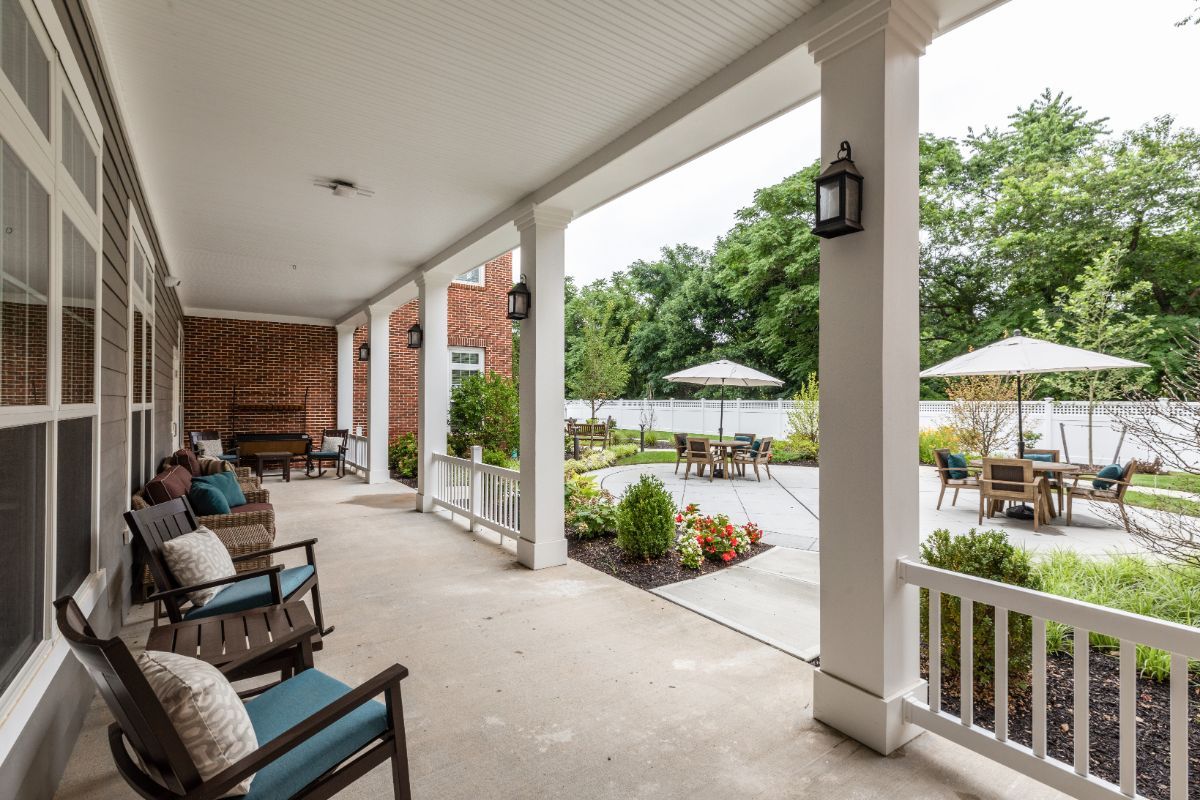 A spacious porch with outdoor seating overlooking a landscaped garden.