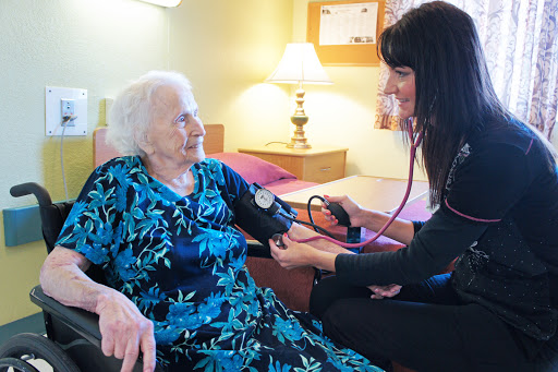 A healthcare professional measures the blood pressure of an elderly patient in a warm, inviting room.