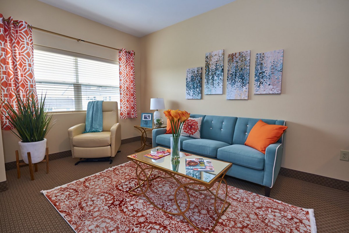 A cozy living room with a teal sofa, patterned rug, and colorful cushions.