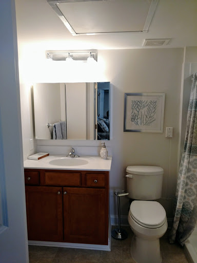 A well-lit bathroom featuring a sink, mirror, and toilet with modern decor.