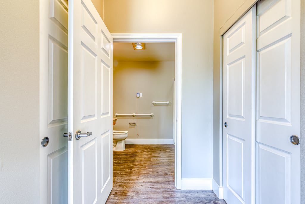 A view of a bathroom accessed through a hallway with doors on either side.