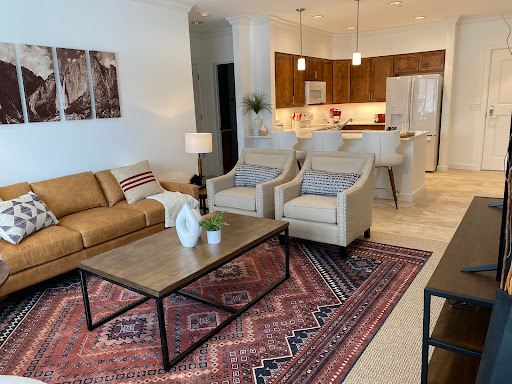A stylish and modern living room featuring a cozy sofa and elegant chairs, complemented by a decorative coffee table and a patterned rug.