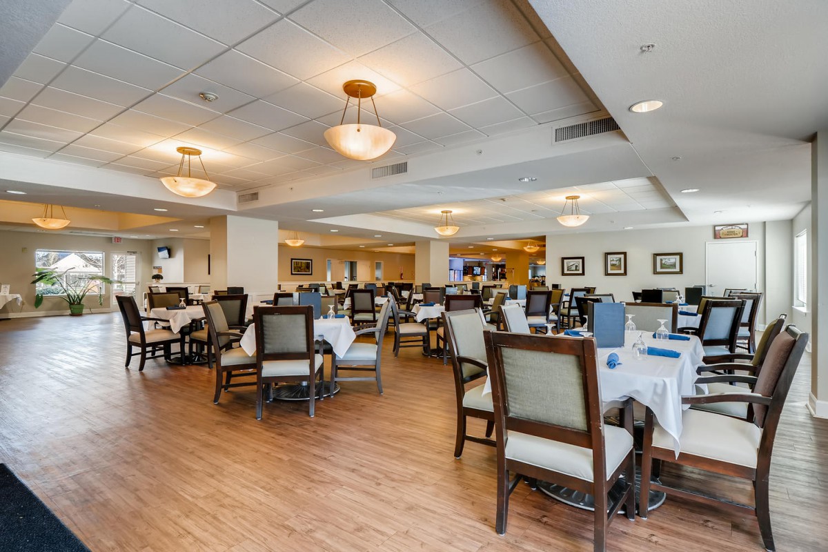 A spacious dining area with multiple tables and chairs, featuring elegant lighting and decor.