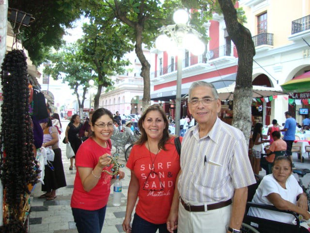 A group of people smiling while walking on a tree-lined street.