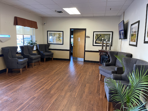 A cozy waiting room featuring comfortable seating, wooden floors, and artwork on the walls.
