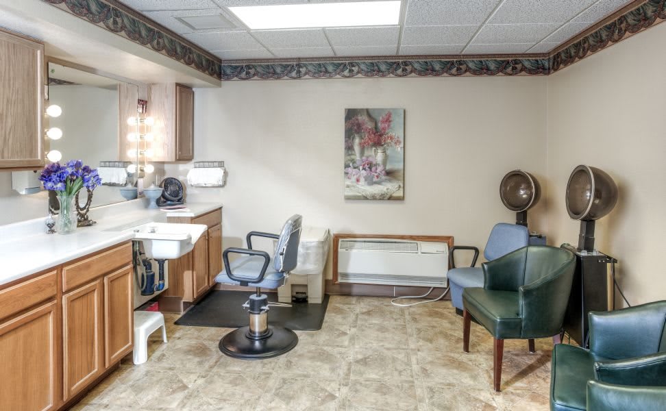 A small hair salon interior with chairs, a sink, mirror, and wall art.
