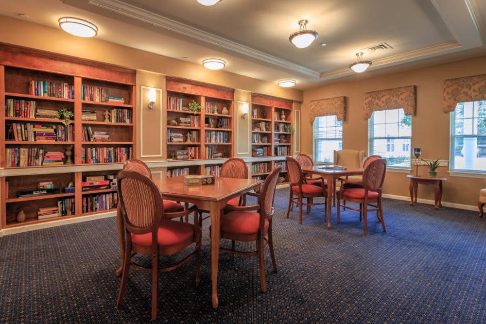 A cozy library reading room with bookshelves, tables, and chairs.