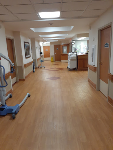 A spacious corridor inside a hospital, featuring wooden flooring and various healthcare equipment.
