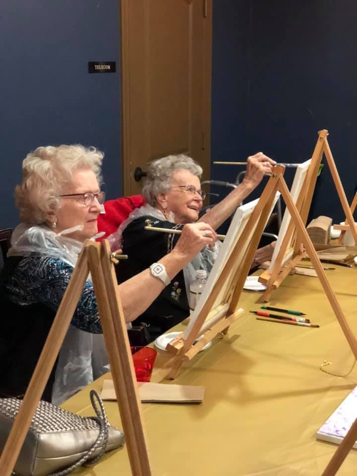 Seniors enjoying a painting class together.