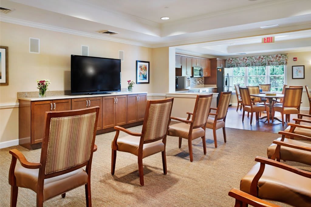 A spacious living room with several chairs arranged facing a large television.