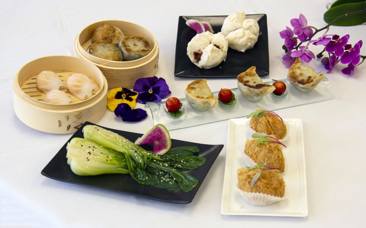 A beautifully presented selection of dim sum dishes, including dumplings and steamed buns, garnished with flowers.