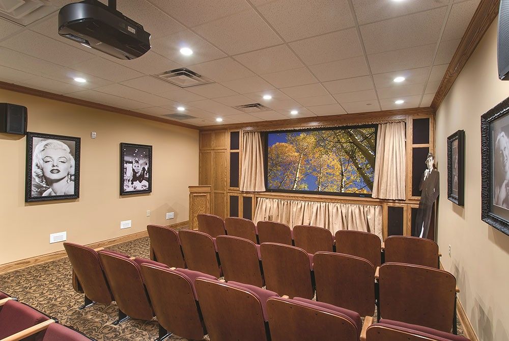 A cozy home theater room with rows of seating facing a large screen.