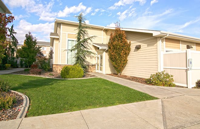 A suburban house with a well-maintained lawn and driveway under a clear sky.