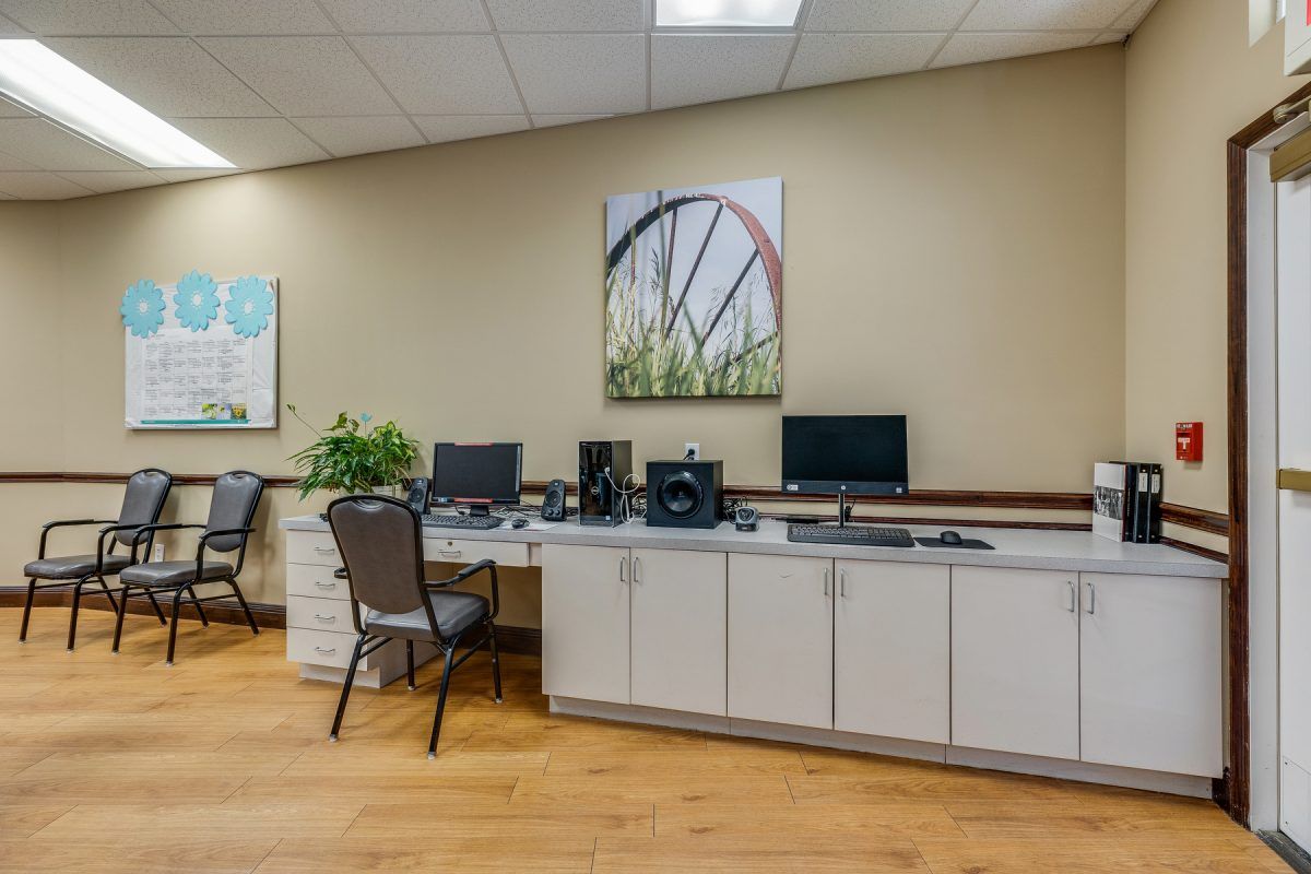 A modern office workspace featuring desks with computers and decorative wall art.