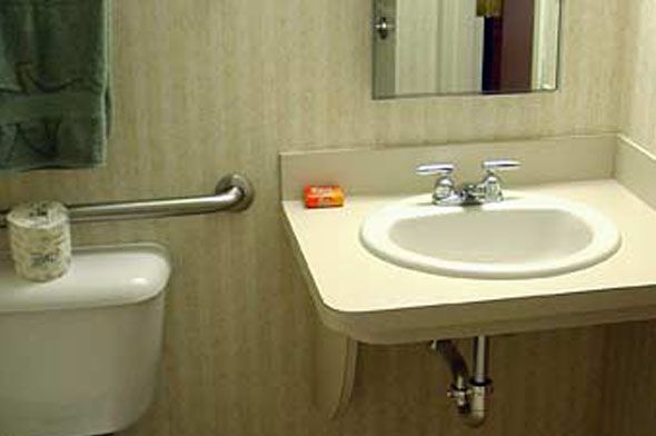 A bathroom with a sink, mirror, and soap on the counter.