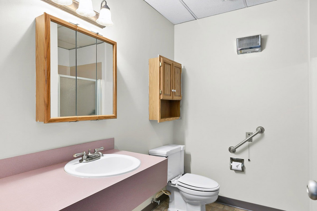 A clean bathroom with a sink, mirror, toilet, and cabinet.