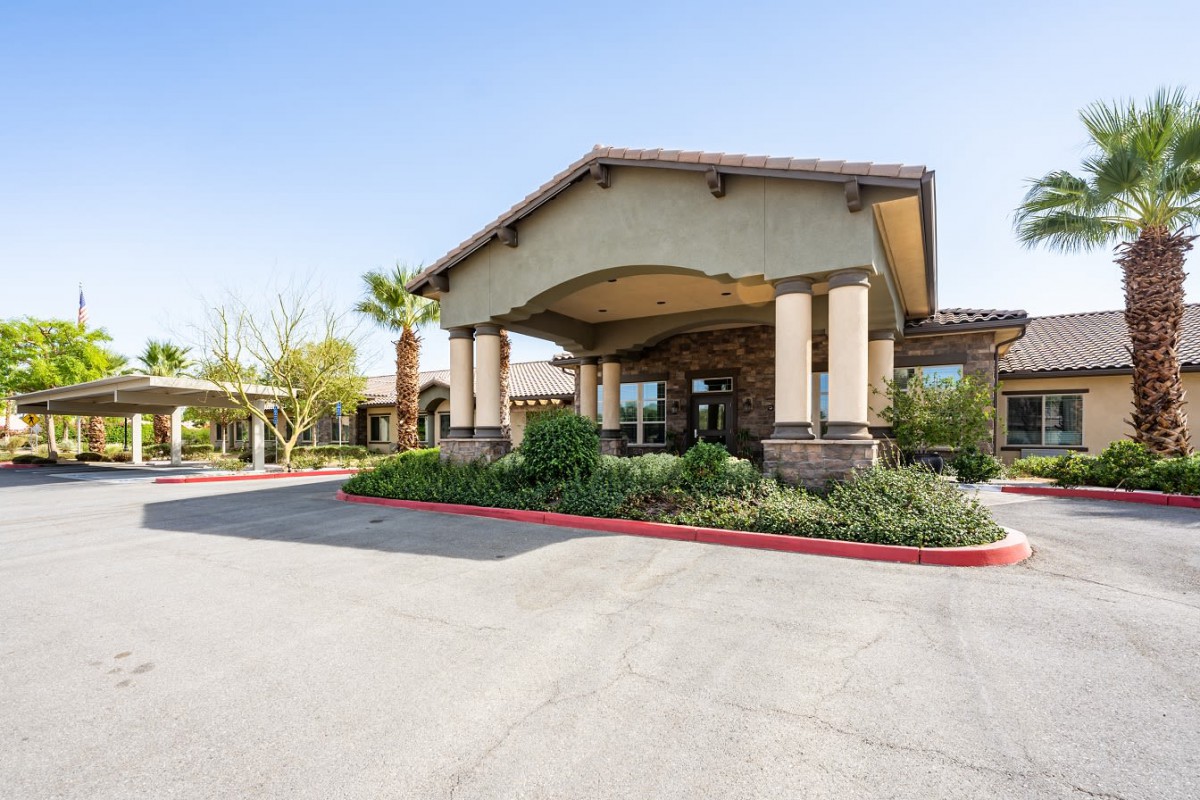 A modern building entrance with a landscaped area and palm tree.