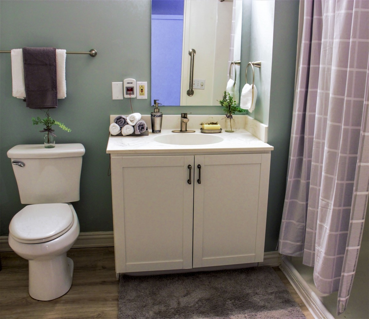 A modern bathroom with a vanity, mirror, and neatly organized amenities.