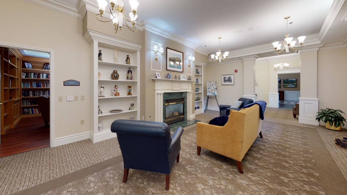 A cozy living room with elegant furniture, a fireplace, and decorative bookshelves.