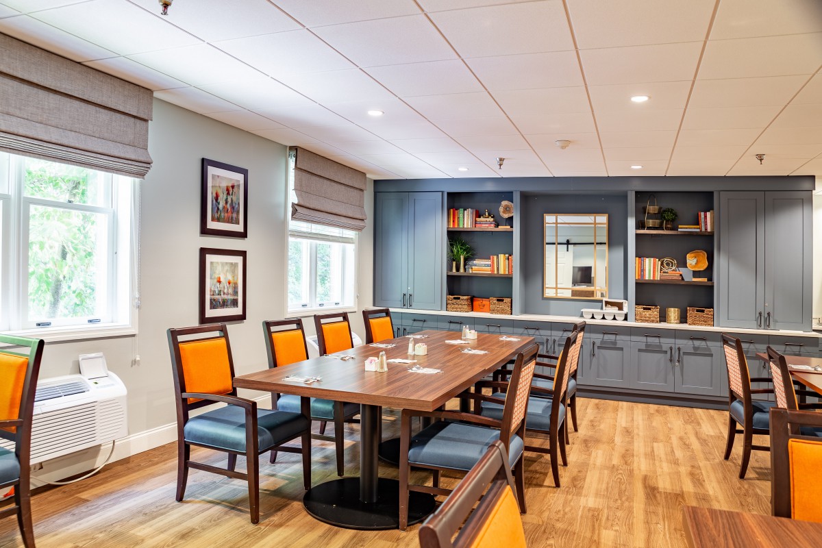 A well-appointed conference room featuring a large table with chairs, decorated with shelves and books.